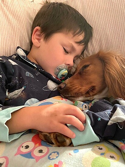 A cachorrinha e a criança estão dormindo juntos.
