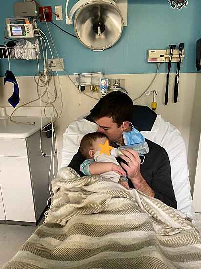Pai está com o bebê no colo no hospital.