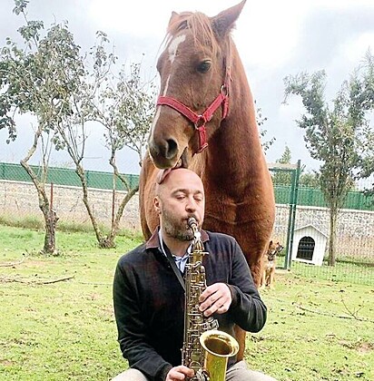 O fazendeiro e empresário está tocando saxofone para seu cavalo