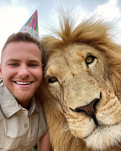 O jovem tirando foto rosto a rosto com um leão.