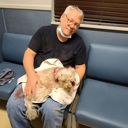 Tim está segurando seu cão no colo enquanto aguarda consulta médica.