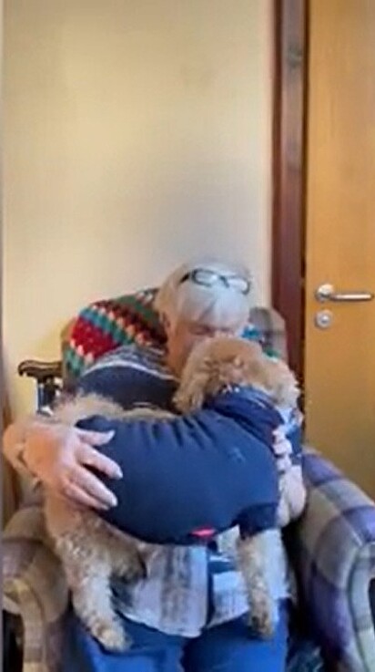 Idosa está abraçando o cão.