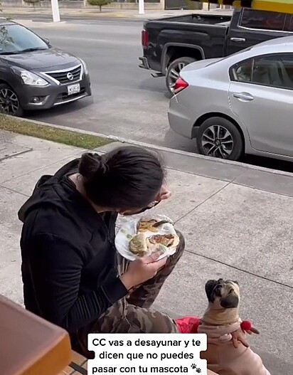 A cachorrinha e o tutor estão na calçada do restaurante.