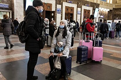 Um casal está na estação com malas e um cachorrinho.