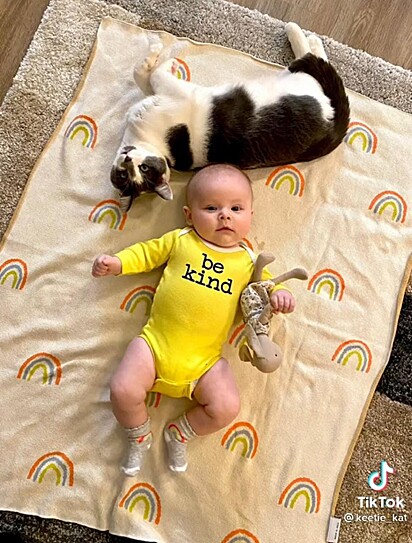 O bebê e o gato estão deitados juntos.