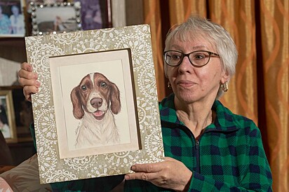 Irene segura nas mãos um quadro do seu amado cãozinho.