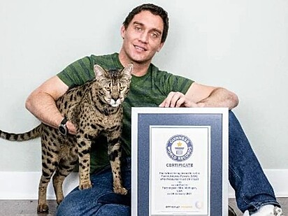 O felino e seu tutor estão junto a um certificado do recorde