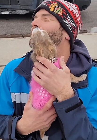 A cachorrinha na maior alegria no colo do rapaz.