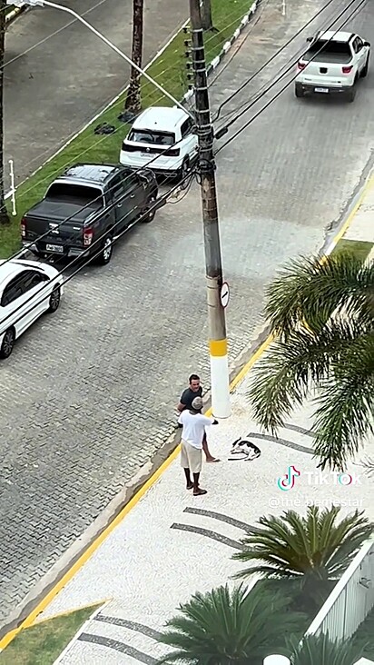 O tutor ficou conversando na calçada do prédio.