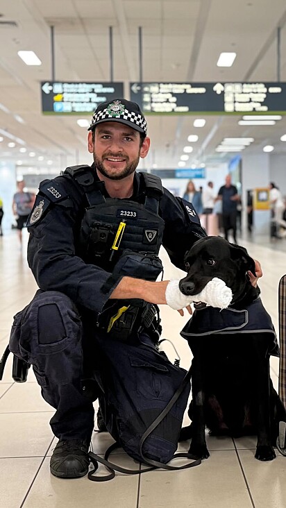 O cão policial Ando ao lado do seu instrutor.