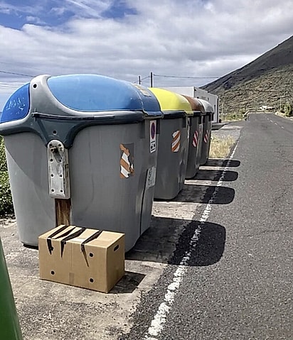 Ao lado das lixeiras, havia uma caixa de papelão lacrada com fita adesiva.