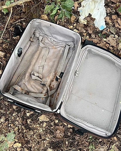 Uma mulher mexia em uma mala abandonada na estrada.