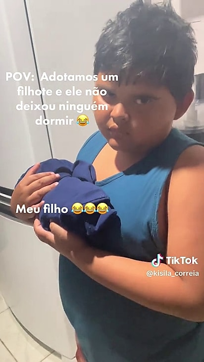 O menino estava com sono mas precisou embalar o filhote.