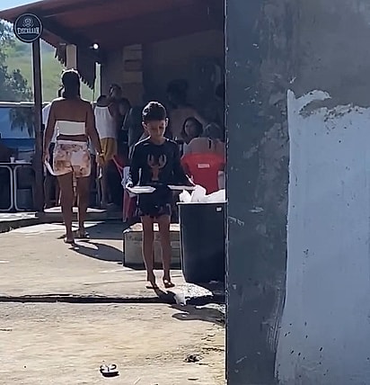 O garotinho juntando comida para dar ao cachorrinho.