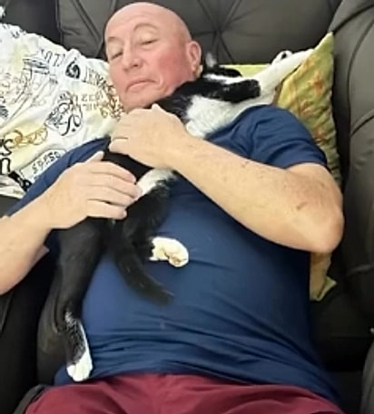 O pai de Gi abraçado à gatinha que apareceu em sua casa.