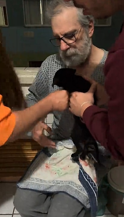 O sogro de Giovanna segurando a cachorrinha por insistência da família.