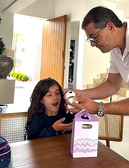 Manu ficou muito contente com a pelúcia, sem imaginar que a verdadeira surpresa ainda estava por vir.