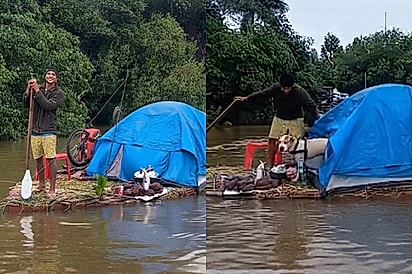 Em dia frio e chuvoso, amigos encontram homem e seu cão vivendo aventura em trapiche no meio do rio.